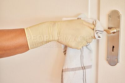Buy stock photo Cropped shot of an unrecognisable man wearing gloves and using a cloth to clean his door handles at home