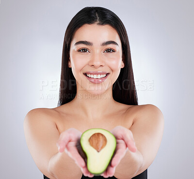 Buy stock photo Studio portrait of an attractive young woman posing with an avocado against a grey background