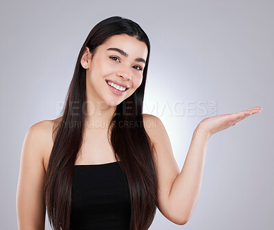 Buy stock photo Studio portrait of an attractive young woman pointing to copyspace against a grey background