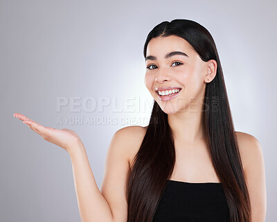 Buy stock photo Studio portrait of an attractive young woman pointing to copyspace against a grey background