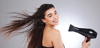 Buy stock photo Studio portrait of an attractive young woman using a hairdryer against a grey background
