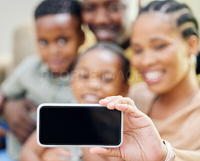 Buy stock photo Shot of an unrecognisable family sitting on the sofa together at home and taking selfies on a cellphone