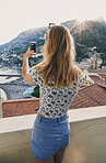 Woman taking photos of Italy coast using smartphone. Rear view of woman taking pictures of ocean view on vacation