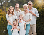 Happy family standing outside in the garden. Smiling senior man and woman relaxing outside with their children and grandchildren. Little girls looking cheerful while enjoying a day in nature