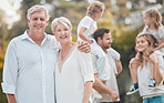 Portrait senior couple and young family members outside in the garden. Happy smiling parents relaxing outside with their children in a park. Portrait of content grandparents with their children and grandchildren at home