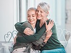 Cheerful senior mother hugging grownup daughter. Loving caucasian mom hugging her daughter while sitting together at home. Senior woman looking happy to see daughter during visit
