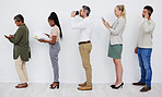 Line of diverse businesspeople waiting in line using tech devices before interview. Group of mature and young business colleagues standing in a row reading reports, drinking coffee before a meeting