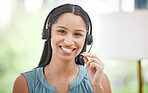 Close Up of a young smiling mixed race call centre agent talking to customers with a wireless technology headset. Hispanic businesswoman answering calls, helping clients from an office. Headshot of a female customer service representative