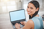 Smiling young businesswoman typing on her laptop keyboard, looking over her shoulder.  Hispanic powerful business professional sending emails from her laptop online. Confident businesswoman at work