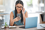 Mixed race business woman wearing glasses while reading text on smartphone. Female entrepreneur sitting at her desk with mobile phone and laptop. Woman browsing on social media or using app in office