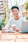 Young asian man or student writing notes and browsing on a laptop outside a cafe. One guy studying or working freelance at a restaurant. Doing research and planning online for blog, work or assignment