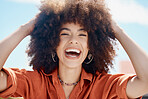 Closeup portrait of African American woman with a beautiful curly afro laughing while touching her natural hair. Black female having fun and looking free while smiling and wearing fashionable clothes