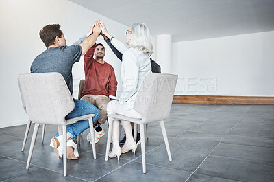 Buy stock photo Diverse group of businesspeople giving each other a high five sitting in a meeting in an office at work. Happy women and men joining their hands for motivation while working together