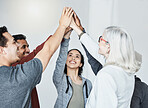 Diverse group of five businesspeople smiling giving each other a high five in a meeting in an office at work. Happy women and men joining their hands in unity standing together while working