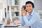 Portrait of one happy young asian male call centre telemarketing agent talking on a headset while working on a computer in an office. Confident and friendly businessman consultant operating a helpdesk for customer service support