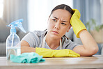A mixed race domestic worker looking depressed while cleaning. One mixed race female bored while cleaning her apartment.