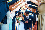 Wedding guests forming a tunnel with their hands as newlywed couple walk through it. Bride and groom leaving their wedding reception