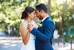Bride and groom dancing outside. Mixed race newlyweds enjoying romantic moments on their wedding day. Happy young romantic couple sharing a dance in nature