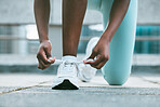 Closeup of one african american woman tying her shoelaces while exercising outside. Black athlete fastening sneaker footwear for a comfortable fit and to prevent tripping during a training workout in the city