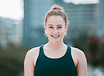 Portrait of one confident young caucasian woman exercising outdoors. Determined female athlete looking happy and motivated for training workout in the city