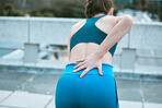 One caucasian woman from behind holding sore lower back while exercising outdoors. Female athlete suffering with painful spine injury from fractured joint and inflamed muscles during workout. Struggling with stiff body cramps causing discomfort and strain