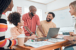 Group of diverse businesspeople having a meeting in a modern office at work. Young cheerful african american businessman laughing and talking to his colleagues while using a laptop. Businesspeople planning together