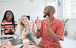 Group of cheerful diverse businesspeople having a meeting in a modern office at work. Joyful colleagues clapping hands for a coworker while sitting at a table. Creative businesspeople planning together