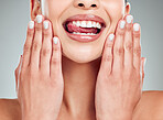 A young beautiful mixed race model with a perfect smile sticking her tongue out while posing against grey copyspace and showing her healthy cuticles after getting a manicure