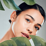 A beautiful mixed race woman posing with a plant. Young hispanic using an organic detox treatment against a grey copyspace background