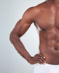 Closeup of one African American fitness model posing topless in a underwear and looking muscular. Confident black male athlete isolated on grey copyspace in a studio wearing boxers showing his sixpack
