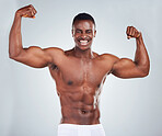 Portrait of a smiling African American fitness model posing topless in a underwear and looking muscular. Happy black male athlete isolated on grey copyspace in a studio wearing boxers