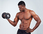 One young African American fitness model posing topless while exercising with dumbbells .Confident black male athlete isolated on grey copyspace while weightlifting in a studio
