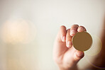 Unknown mixed race woman holding a concept gold coin against a bokeh background with copyspace. Hispanic woman budgeting finances and investing in future currency and money like cryptocurrency bitcoin