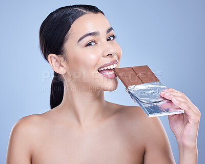 Buy stock photo Studio portrait of a beautiful mixed race woman holding a slab of chocolate. Hispanic model snacking on dessert against a blue copyspace background