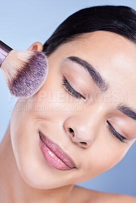 Buy stock photo A beautiful mixed race woman posing with a makeup brush during a pamper routine. Hispanic model holding a contouring brush against a blue copyspace background