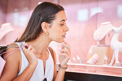 Buy stock photo Young woman looking at jewellery on display through a window during a shopping spree in a mall. One female only enjoying retail therapy. Shopaholic holding bags and deciding whether to buy accessories