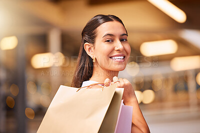 Buy stock photo Portrait of a Young mixed race woman during a shopping spree in a mall. One hispanic female only enjoying retail therapy. Shopaholic holding bags smiling and looking happy while walking in a shopping mall