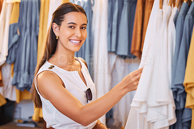 Buy stock photo Young hispanic woman smiling while shopping for clothes at a shopping mall. Happy woman looking through clothing rails. Relaxing and enjoying shopping on the weekend