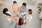 Group of happy businesswomen stacking their hands together in an office at work. Diverse group of businesspeople having fun standing with their hands stacked in support from above