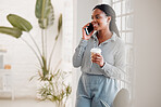 Young african american businesswoman on a call using her phone while drinking a coffee alone in an office at work. One black woman talking on her cellphone and holding a coffee cup on a break standing at work