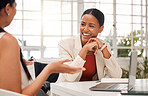 Two young happy mixed race businesswomen laughing while having a meeting in a boardroom at work. Cheerful businesspeople talking while planning together in an office