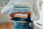 hands of a woman holding a pile of laundry. Woman holding a stack of neat, folded laundry. Woman cleaning clothing at home. Woman carrying a pile of fresh, cleaned clothing at home