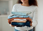 Woman cleaning a pile of laundry. Woman holding a stack of neat, folded clothing. Hands of a woman doing housework chores. Hispanic woman holding fresh, washed clothing and bedding.