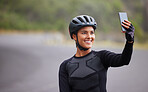 One athletic young woman taking a selfie using her smartphone during a break from cycling outside. Sporty fit mixed race female wearing a helmet and having poor reception