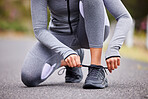 Unknown fit woman tying the laces of her sneakers for exercise outdoors. Unrecognizable athlete fixing her shoes to get ready for a run or jog in the morning. Preparing for a refreshing cardio workout