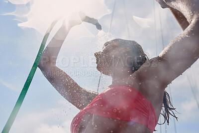 Buy stock photo Woman in red bikini using hose to shower on boat after swimming. Woman using a hose to shower on a boat. Young woman showering herself on a boat using a hose
