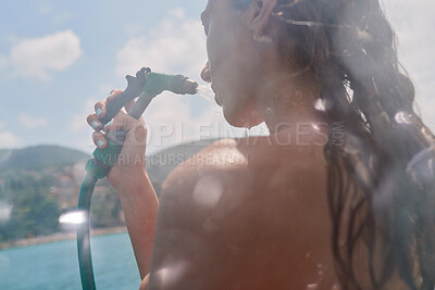 Buy stock photo Young woman using hose to spray her face on boat during shower. Woman showering herself using a hose spraying her face. Young woman showering on boat after swimming