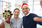 Group of three cheerful diverse businesspeople taking a selfie together at work. Happy mixed race businessman taking a photo with his joyful female colleagues at a Christmas office party