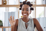 Young cheerful African american businesswoman waving her hand while sitting at a table in an office. Joyful black female businessperson making a hand gesture and greeting at work