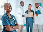 Mature african american female doctor standing with her arms crossed while working at a hospital. One expert medical professional smiling while standing at work with colleagues at a clinic